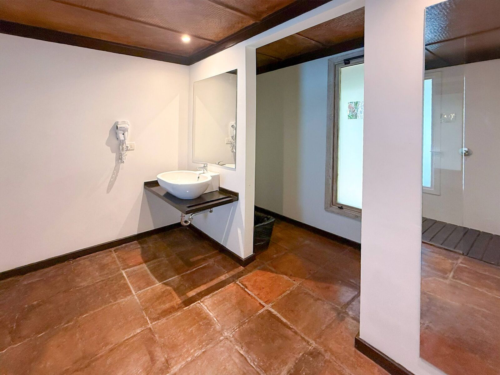 Clean cabana bathroom with terracotta floor tile and a glass walk-in shower
