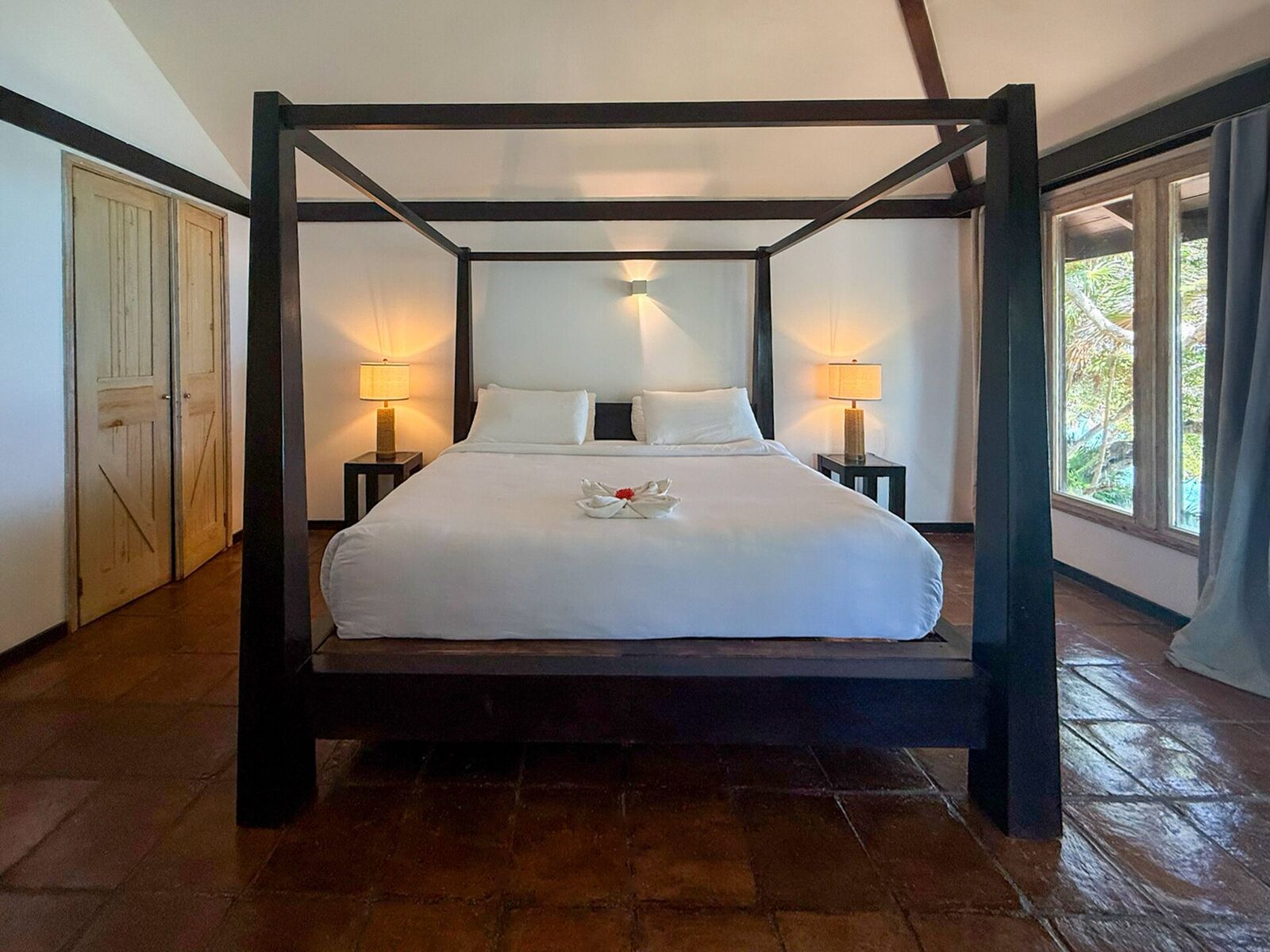 Bright resort bedroom with two beds and a vaulted wooden ceiling
