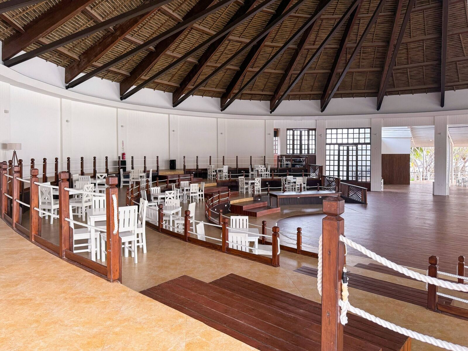 Tropical resort restaurant with a thatched roof and tiered open-air seating
