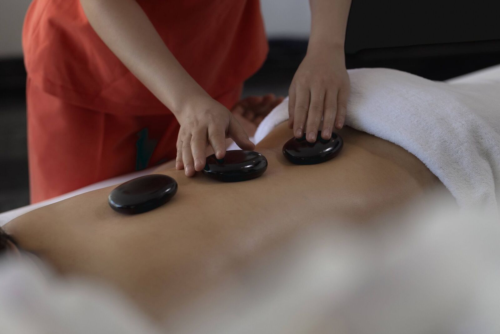 Spa therapist performing a hot stone back massage